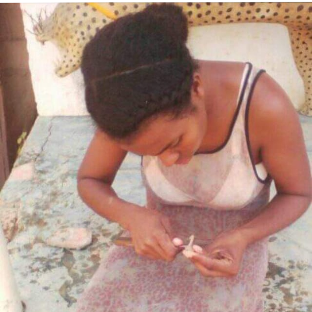Woman sitting on a stone surface wearing a patterned dress.