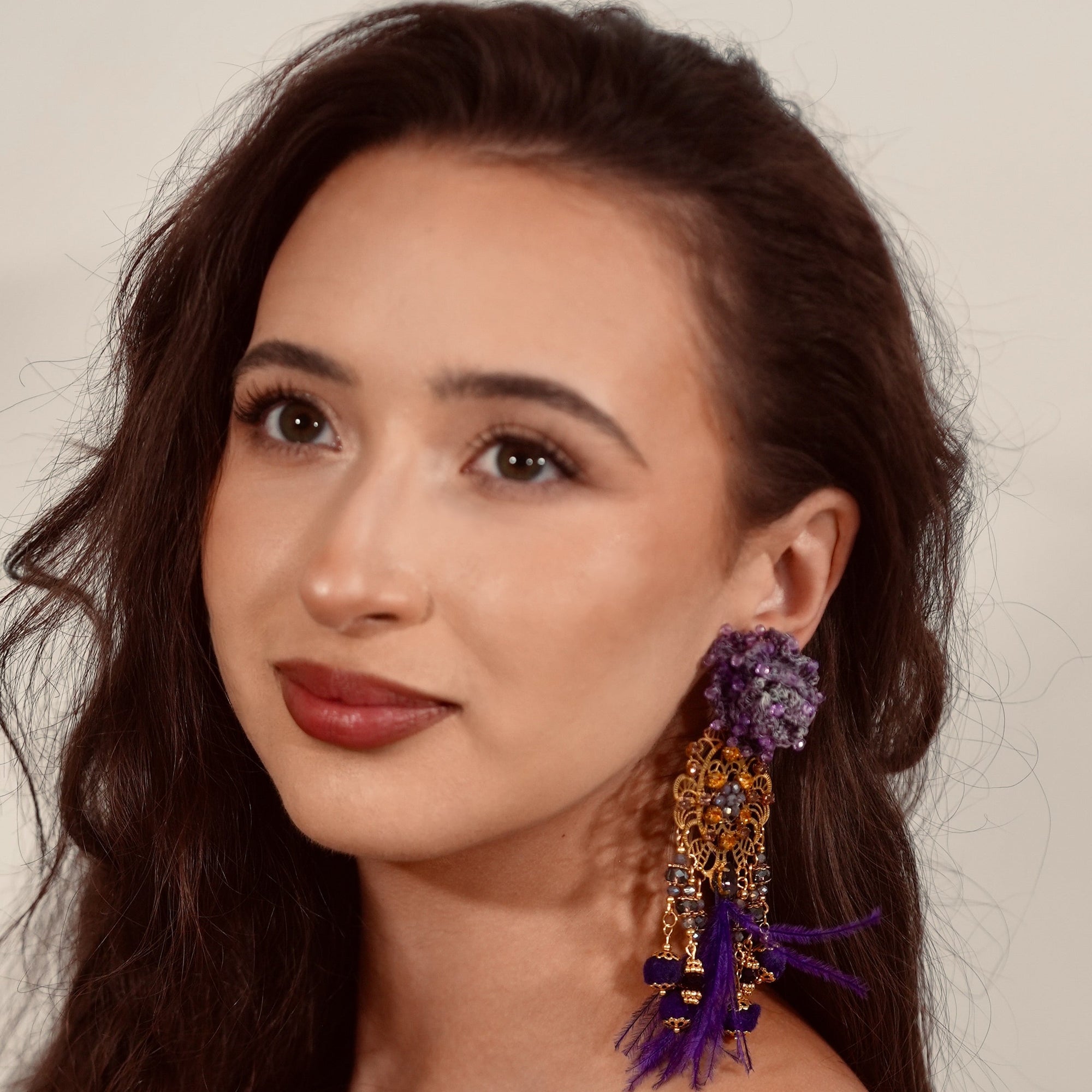 Woman wearing colorful earrings against a neutral background