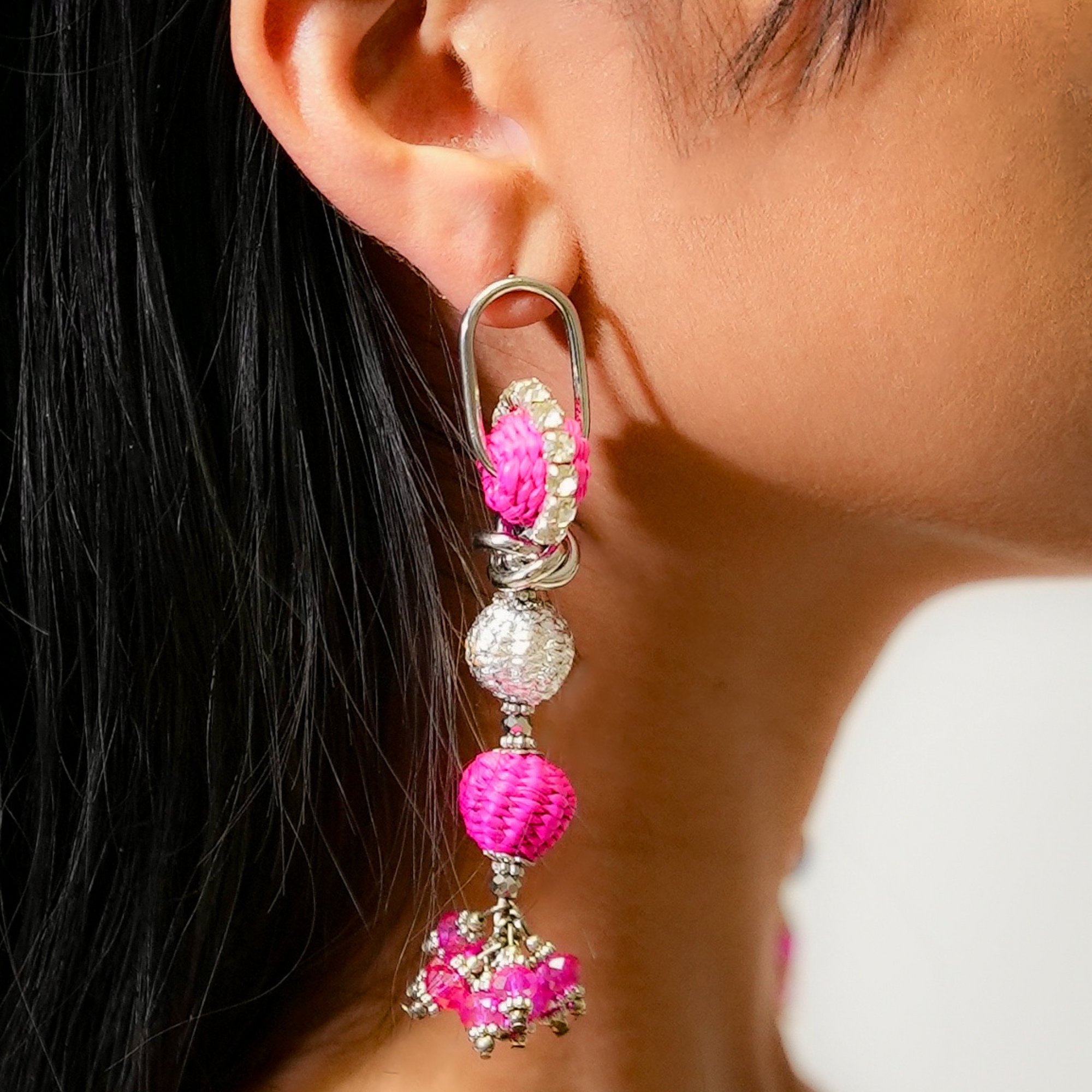Close-up of a person wearing pink and silver beaded earrings.