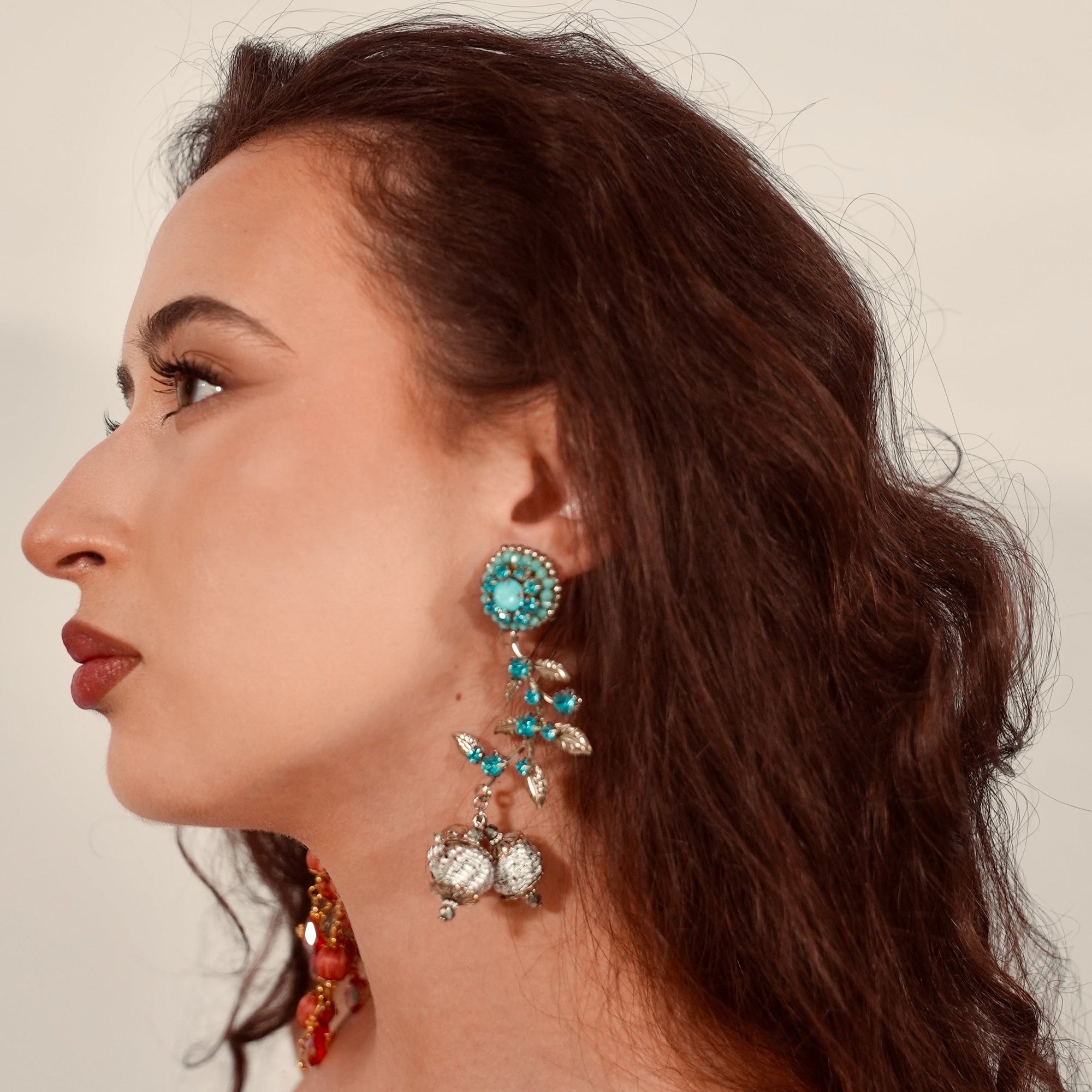 Woman wearing turquoise earrings with a neutral background
