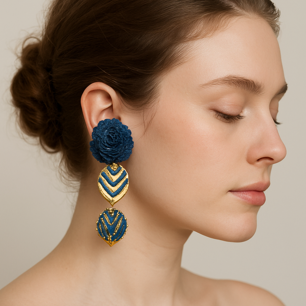 Model wearing Indigo Bloom Earrings with blue floral tops, gold medallions, blue rhinestones, and green gemstone drops — artisan handcrafted