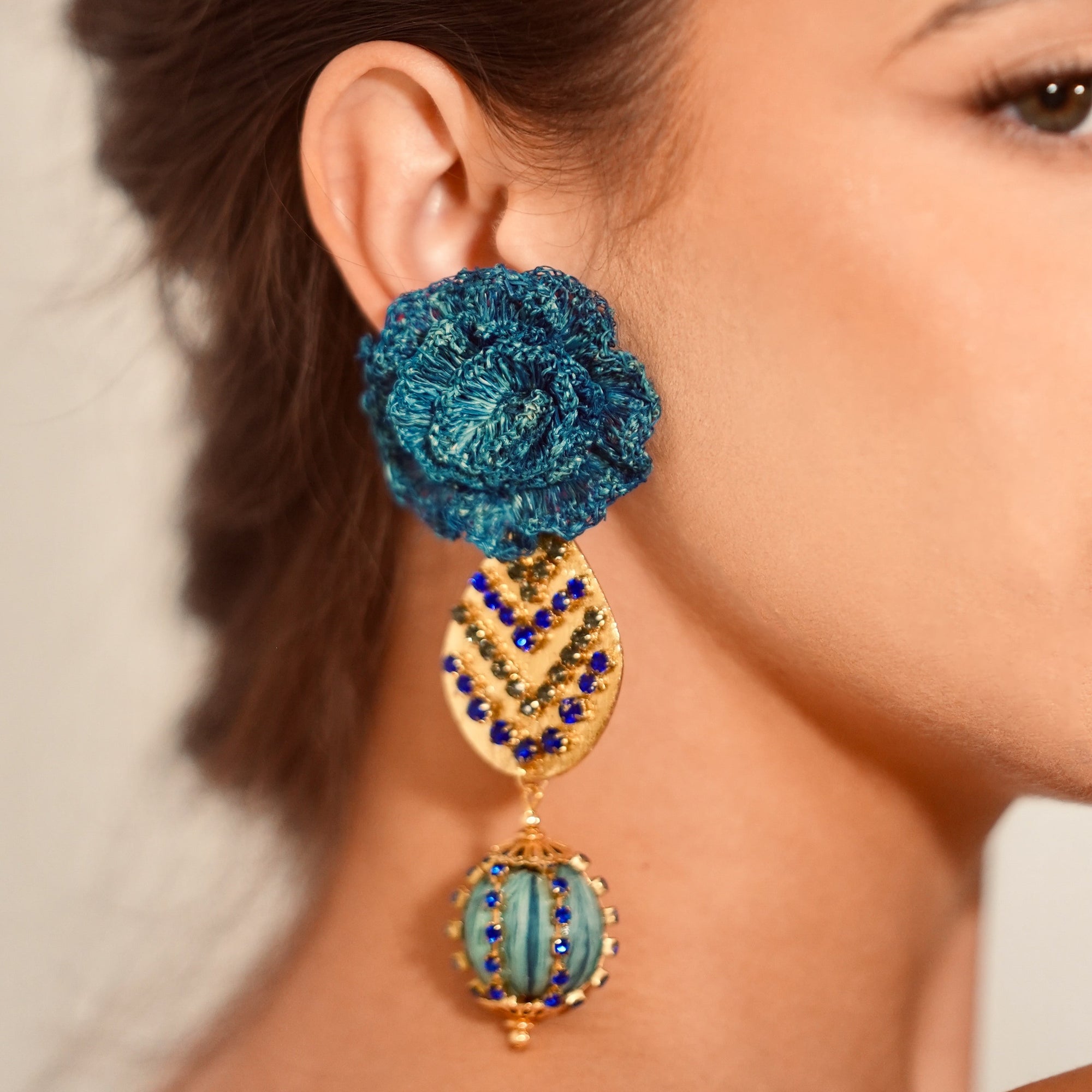 Close-up of a woman wearing a blue and gold earring.