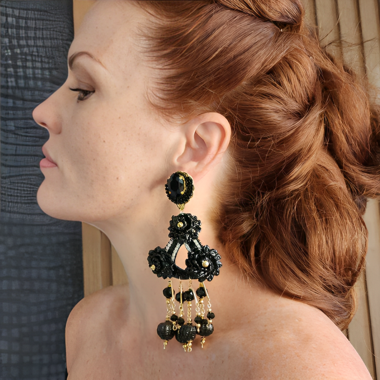 A person wearing a black and gold fiber oval flower earring with day and night design.