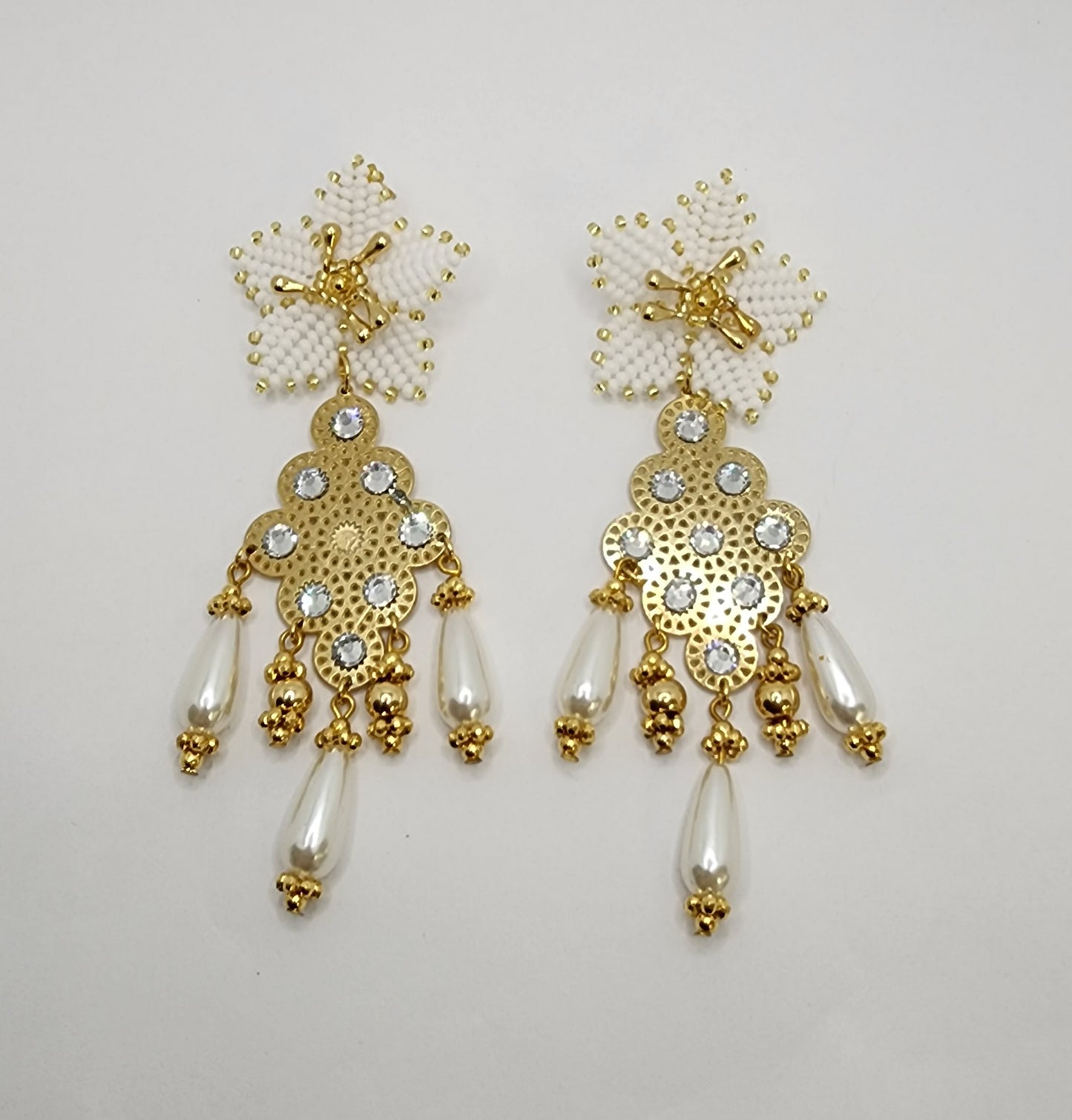 Handcrafted gold chandelier earrings with floral tops, rhinestones, and pearl-like teardrops.