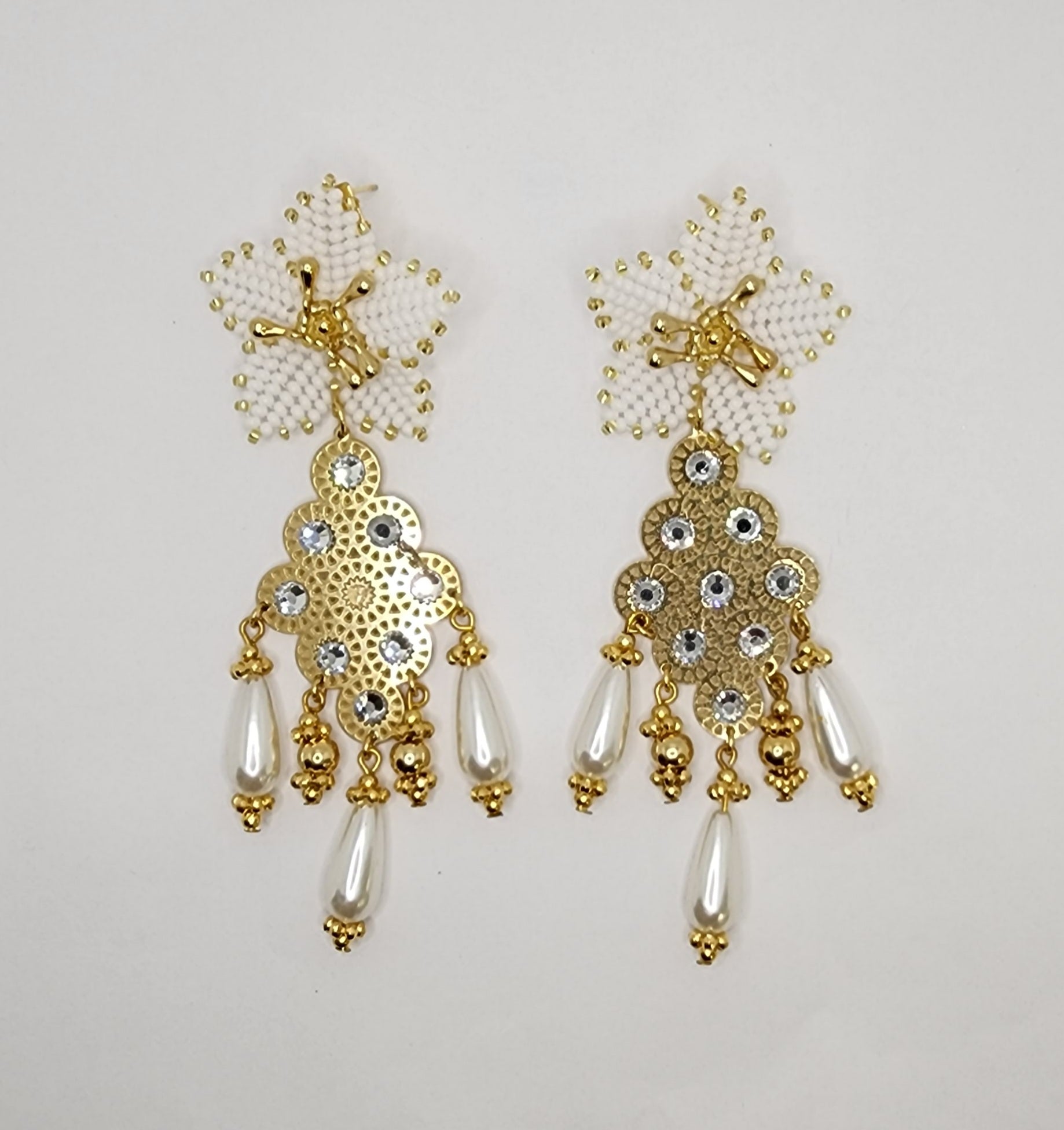 Handcrafted gold chandelier earrings with floral tops, rhinestones, and pearl-like teardrops.