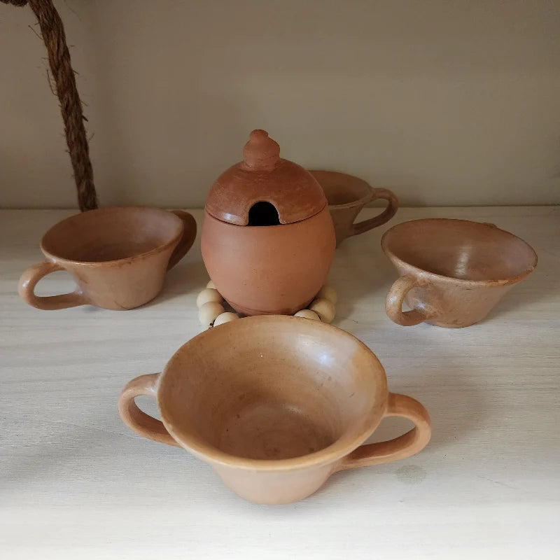 This handcrafted clay set includes four terracotta cups with handles and a charming jar with a lid, perfect for serving hot beverages or storing sugar and small ingredients.