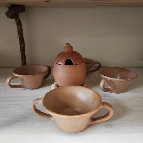 This handcrafted clay set includes four terracotta cups with handles and a charming jar with a lid, perfect for serving hot beverages or storing sugar and small ingredients.
