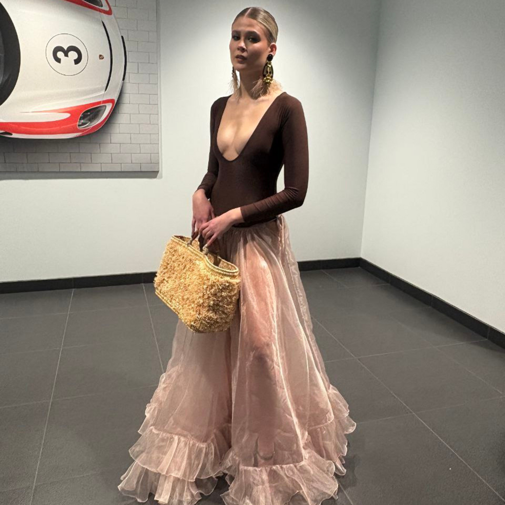 Model posing with Iraka Leather Beach Bag in an elegant setting, styled with a long sheer tulle skirt