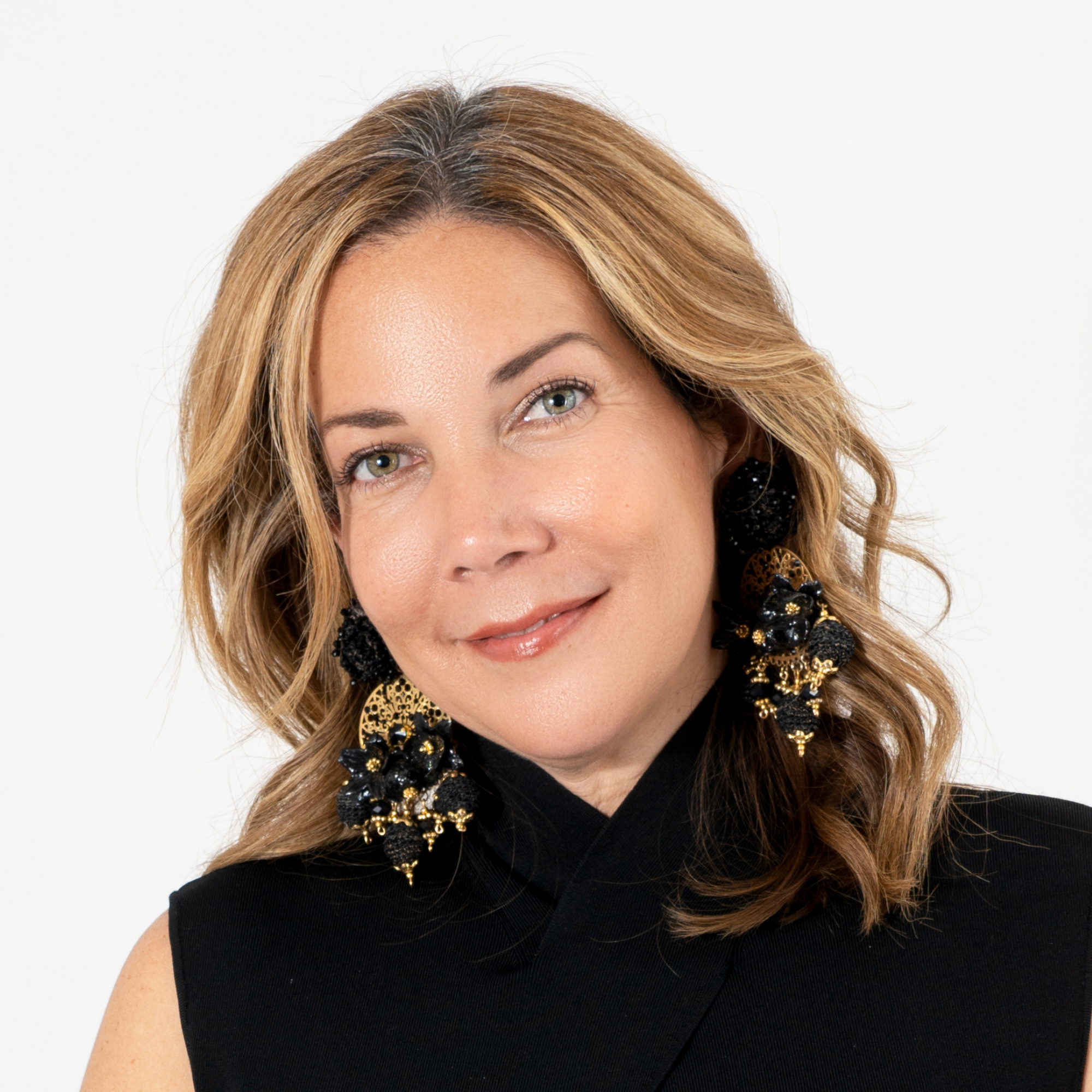 Smiling woman wearing black and gold floral earrings with intricate handcrafted details and bold design.