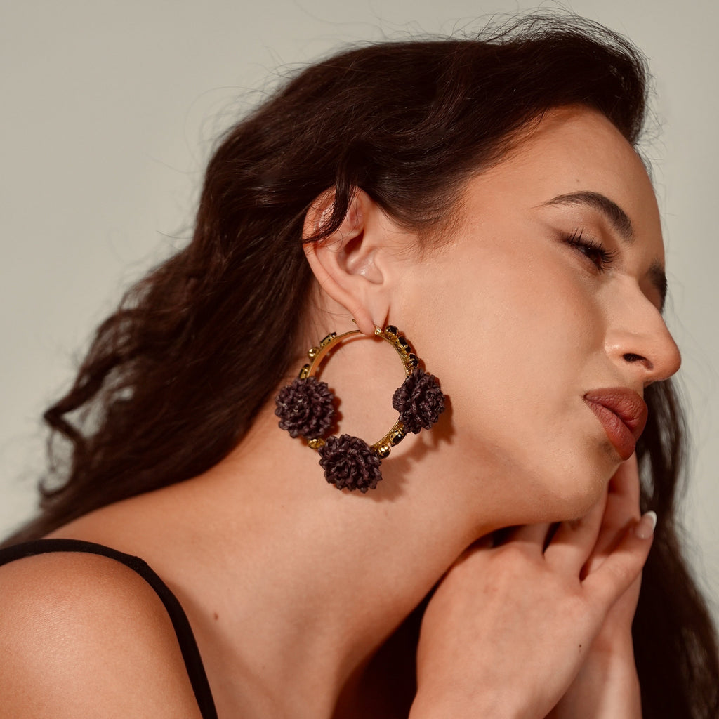 Woman wearing large hoop earrings with a neutral background
