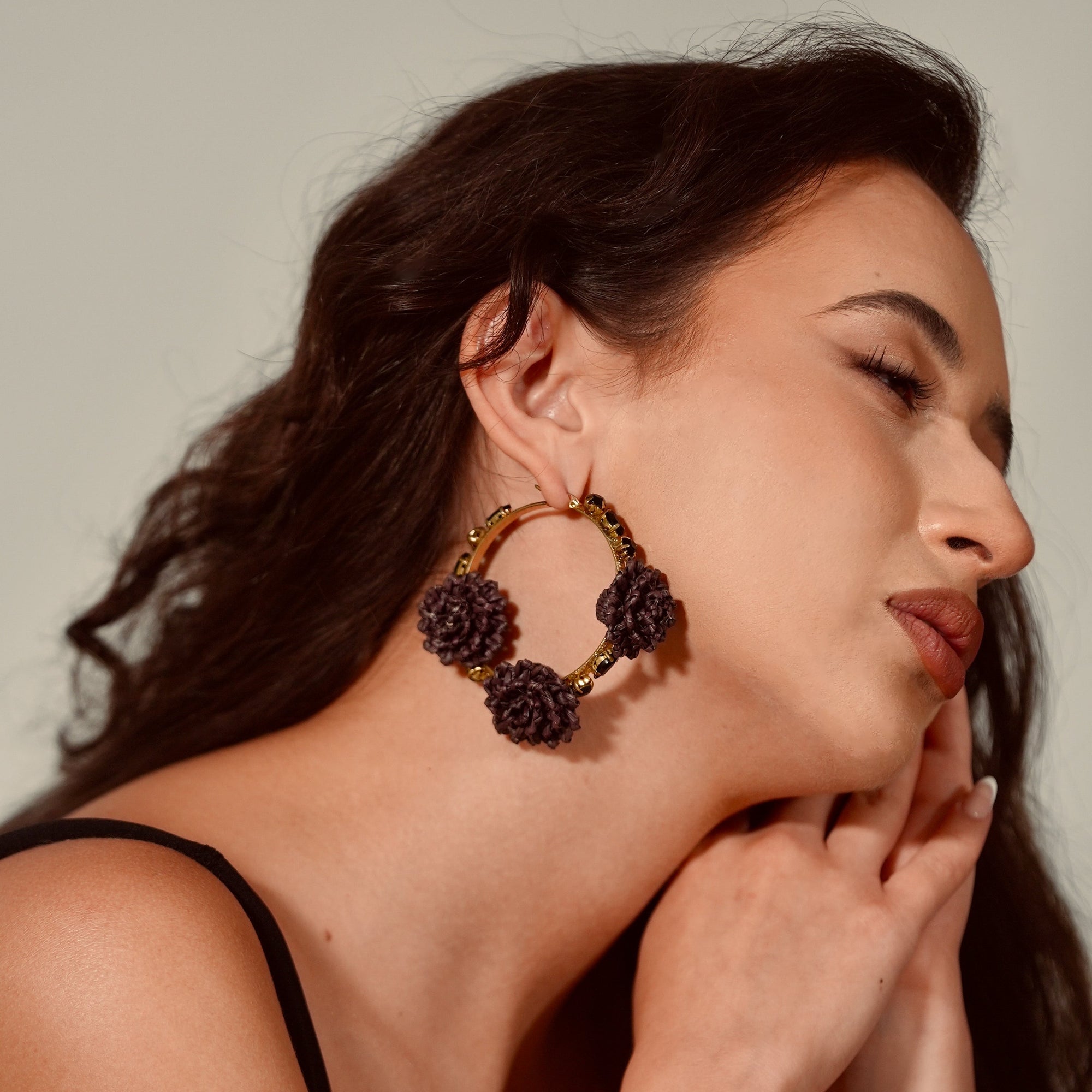 Woman wearing large hoop earrings with a neutral background