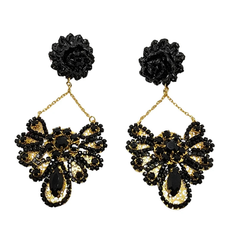 The Bloom Fan Statement Earrings exude dramatic elegance and intricate craftsmanship. Featuring a bold woven floral stud, these earrings cascade into a gold-tone fan-shaped drop, embellished with either deep purple floral appliqués or black gemstones.