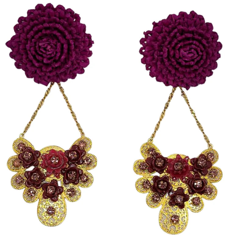 The Bloom Fan Statement Earrings exude dramatic elegance and intricate craftsmanship. Featuring a bold woven floral stud, these earrings cascade into a gold-tone fan-shaped drop, embellished with either deep purple floral appliqués or black gemstones.