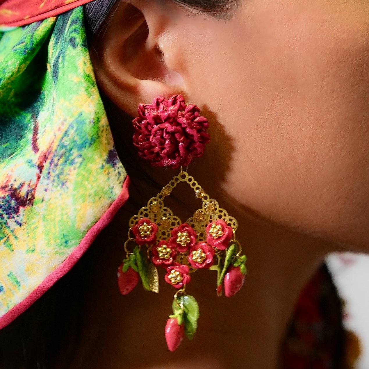 Close-up of a person wearing colorful earrings with floral designs.