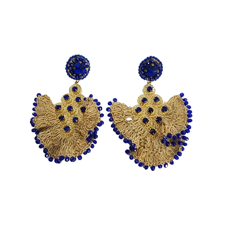 These handcrafted earrings by Colombian artisans are shaped like a crescent moon, made from banana fiber and enhanced with a golden sheet. Adorned with vibrant blue gemstones, they add a touch of elegance and color to any outfit.