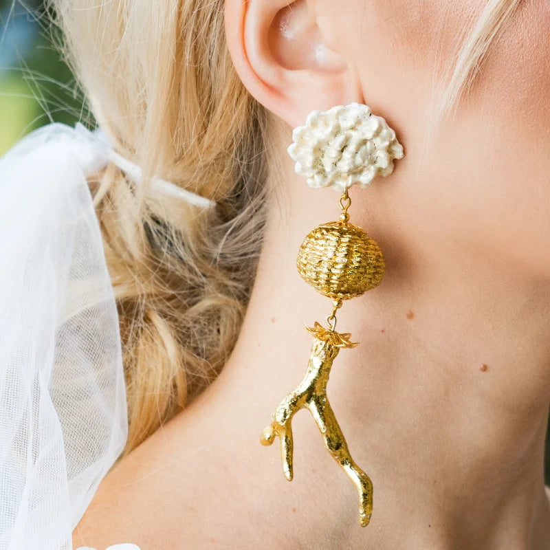 These earrings showcase a unique and striking design inspired by the beauty of organic textures. Featuring intricate golden coral details and delicate pearl-like flowers, they exude elegance and sophistication.
