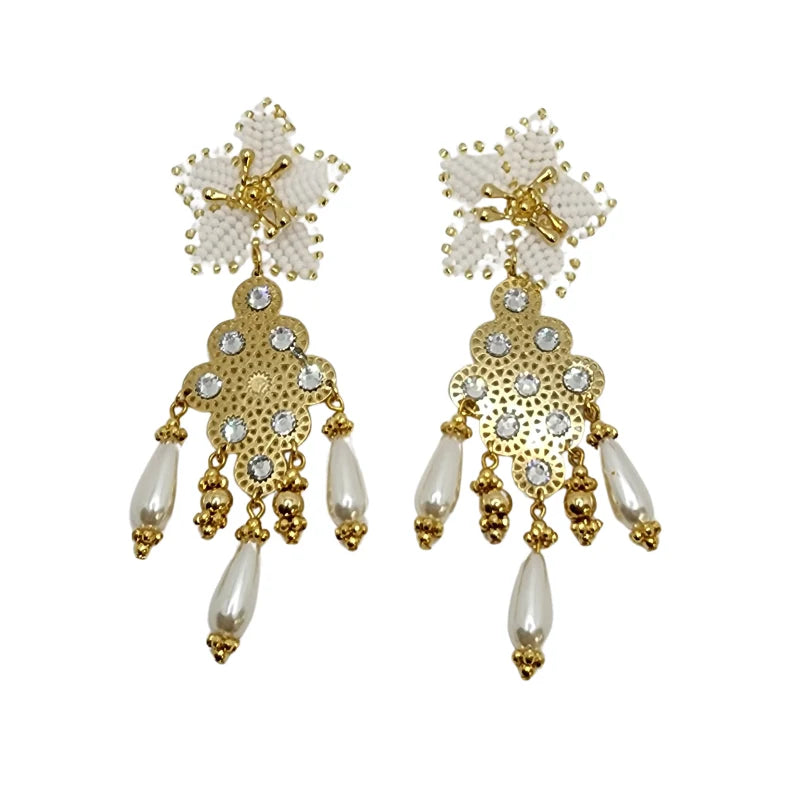 These beautiful earrings feature intricate gold designs, crystal embellishments, and dangling pearl-like beads. A delicate white beaded floral motif at the top enhances the elegance of the design, making them perfect for formal or festive occasions.