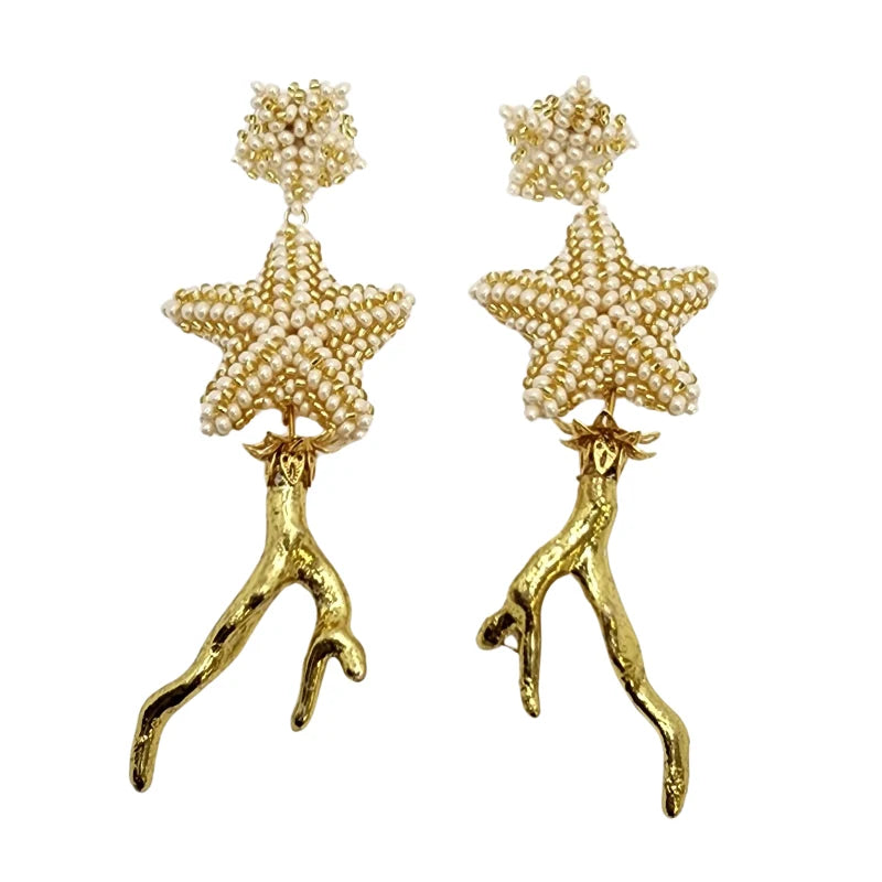 These stunning bridal dangling earrings feature stars delicately woven with white pearls and gold accents shaped like organic branches. Inspired by marine elegance and sophistication, they are the perfect accessory for brides seeking a unique and refined look on their special day.
