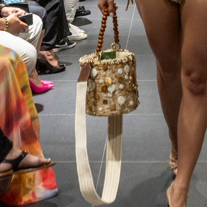 Model holding the Pearl Coral Bag on a runway, highlighting the pearl and shell embellishments and wooden handle.