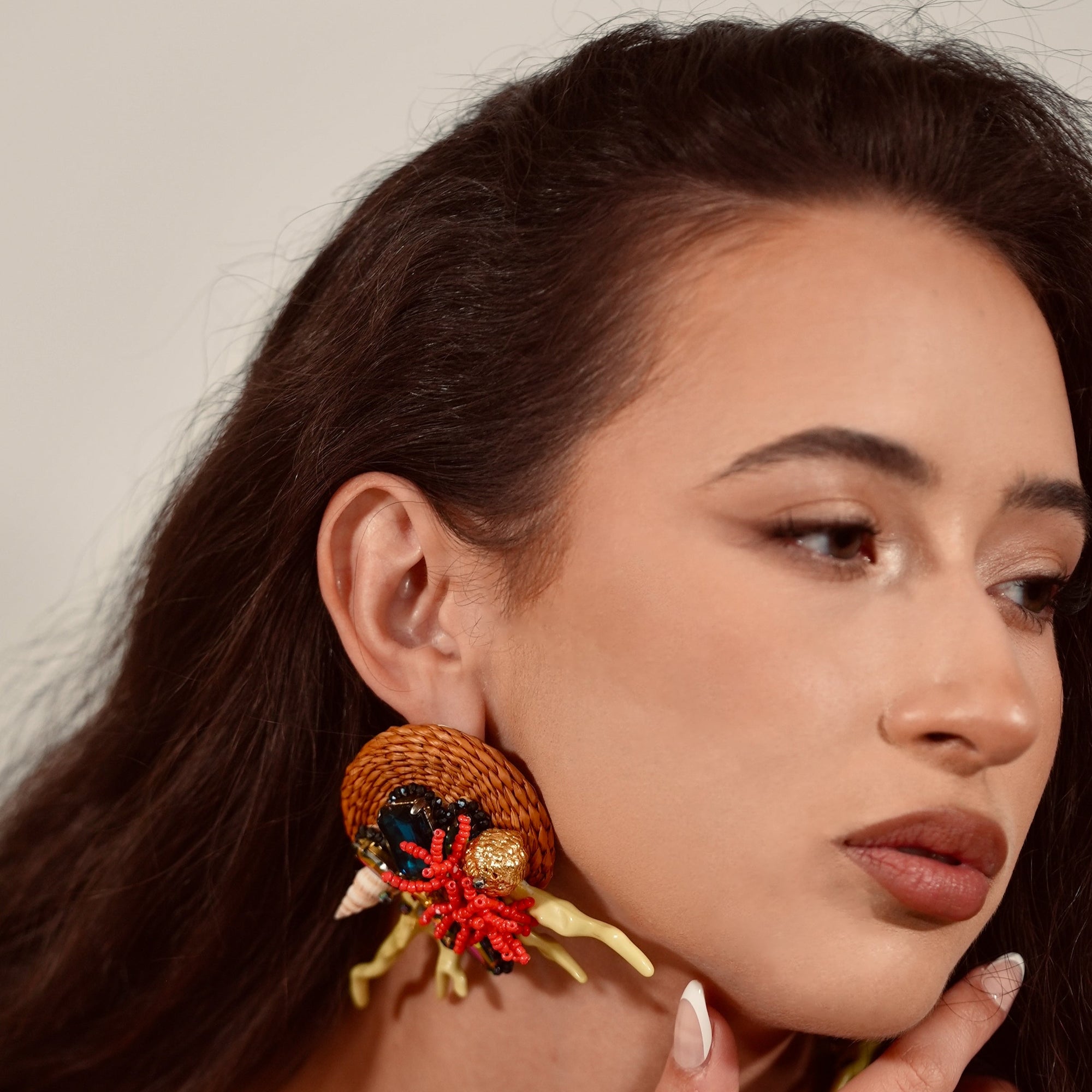 Woman wearing large, ornate earrings with a neutral background