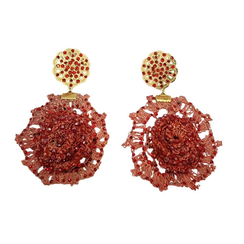 These handcrafted earrings feature a gold-tone circular ornament with perforated details and small red stones for a sophisticated shine.