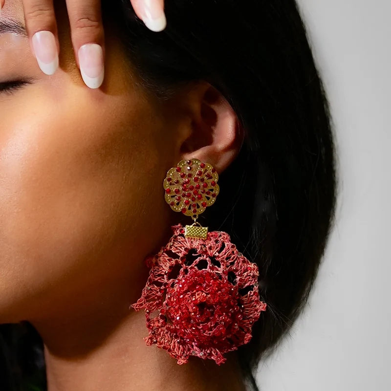 These handcrafted earrings feature a gold-tone circular ornament with perforated details and small red stones for a sophisticated shine.