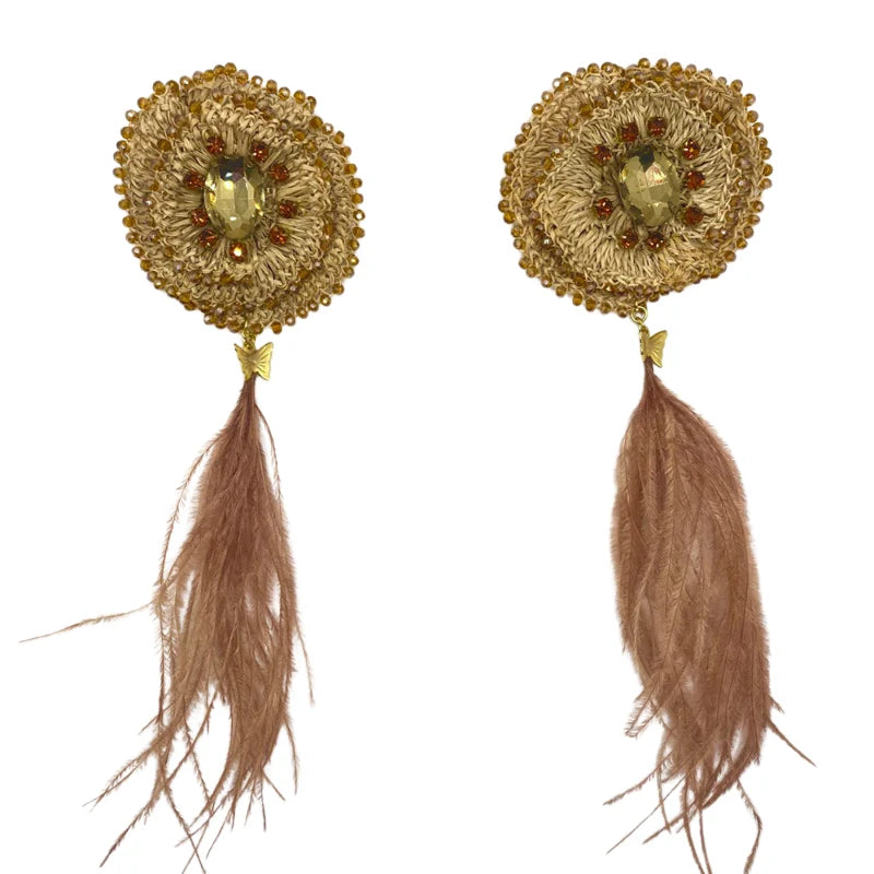 These stunning dangling earrings are handcrafted with Banana Tree Fibers, featuring delicate feathers in a soft, nude color. The design is inspired by God’s wonder, capturing the essence of a dazzling golden hue akin to the morning sun. Adorned with tiny dangling flowers, fiber beads, and subtle feathers, they embody elegance and grace