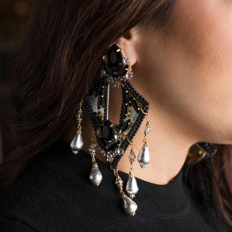 These earrings are crafted from totumo in a rhombus shape, painted silver with fine black and silver gemstones.