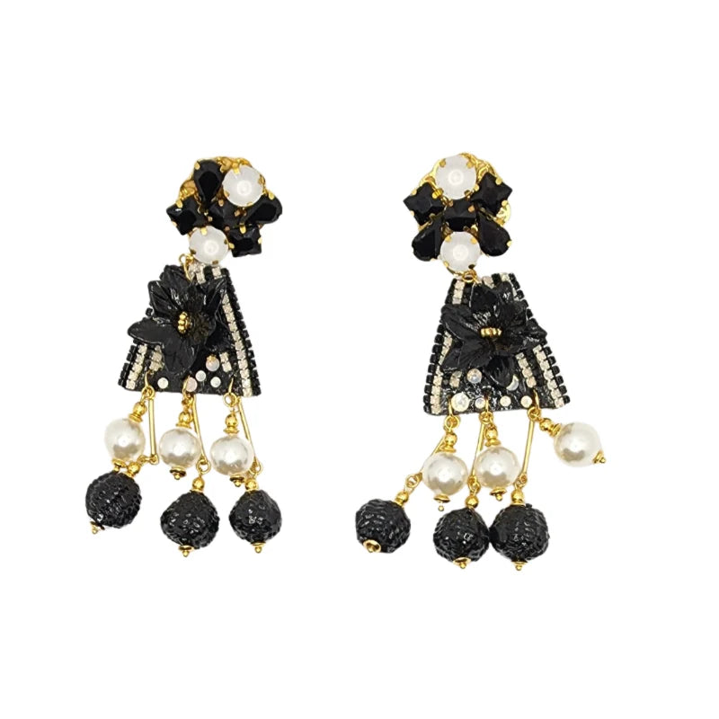 A pair of black and white earrings featuring banana tree fiber painted flowers, painted fruit, gemstones, and Murano stones.
