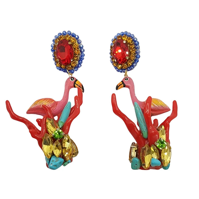 A pair of colorful earrings featuring a flamingo design with sun, feathers, flowers, and birds in a harmonious composition, with Murano stones and dangling fiber beads.