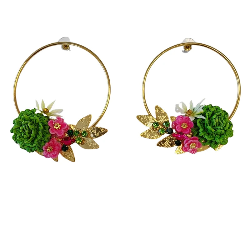 These stunning golden earrings feature delicate handcrafted flowers made from banana fiber, painted in vibrant green, white, and fuchsia