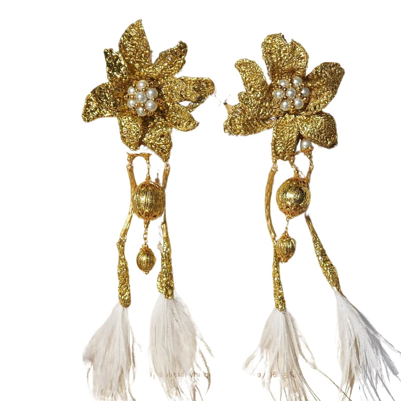 These majestic earrings feature a big flower design crafted with gold-plated Banana Tree Fibers, utilizing a new and innovative technique. The earrings are adorned with dangling feathers, adding an elegant and dynamic touch.