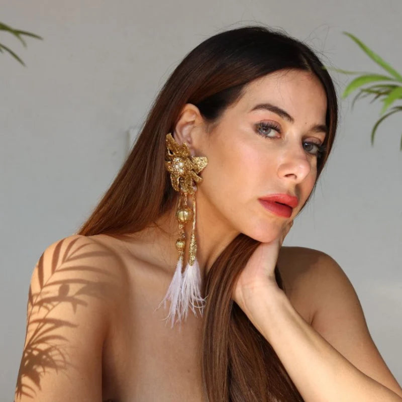 These majestic earrings feature a big flower design crafted with gold-plated Banana Tree Fibers, utilizing a new and innovative technique. The earrings are adorned with dangling feathers, adding an elegant and dynamic touch.