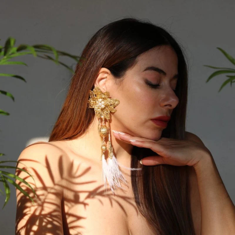 These majestic earrings feature a big flower design crafted with gold-plated Banana Tree Fibers, utilizing a new and innovative technique. The earrings are adorned with dangling feathers, adding an elegant and dynamic touch.