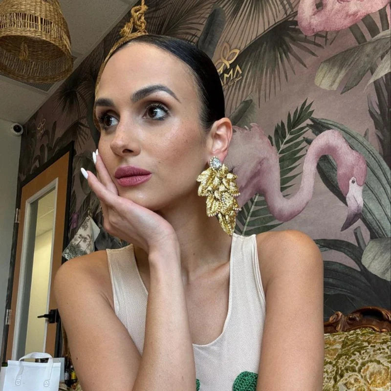 Woman wearing gold earrings and a watch in a room with decorative wallpaper