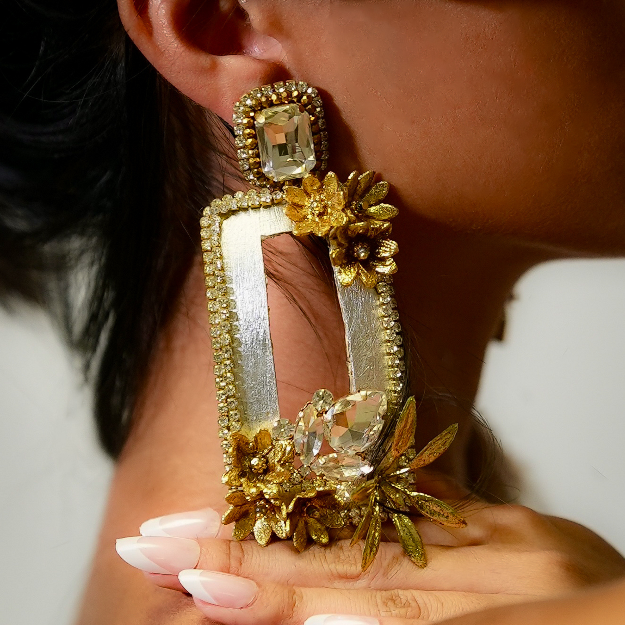 Close-up of a person wearing a gold and silver earring with floral design.