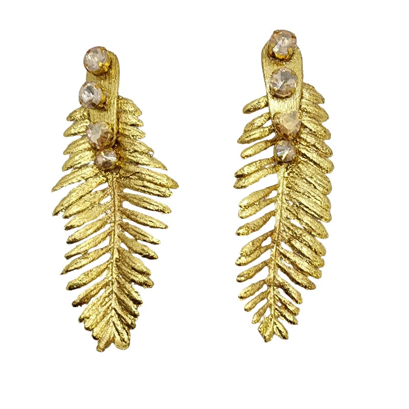 These dazzling earrings, crafted from banana fiber, are inspired by the delicate structure of fern leaves. Adorned with sparkling crystals, their intricate gold design adds a touch of nature-inspired luxury to any outfit.