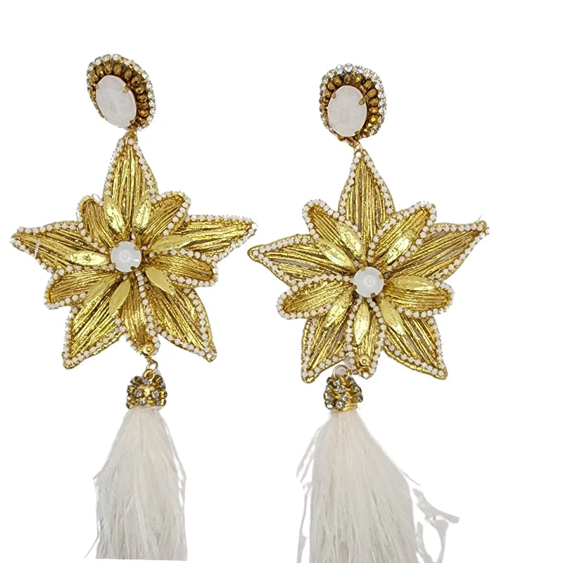 Handcrafted by Colombian artisans, these earrings feature double banana fiber flowers painted in gold, adorned with white gemstones, and finished with white feathers.
