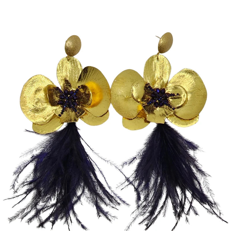 These handmade earrings crafted by Colombian artisans feature banana fiber material painted in gold and adorned with purple feathers.
