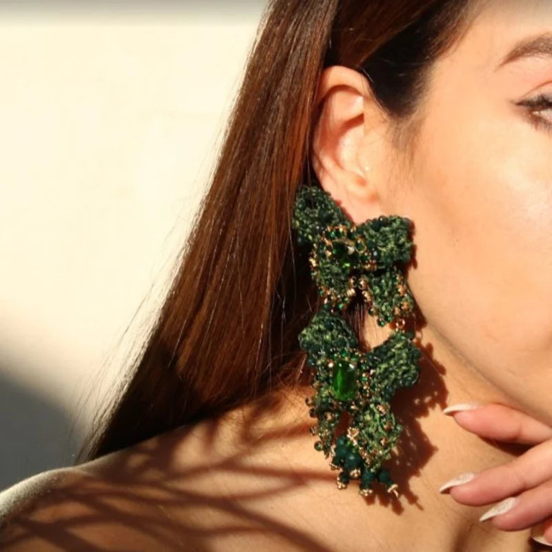These stunning earrings feature two large, beautiful bows, delicately decorated with Murano stones, symbolizing the joy of gifting. Handcrafted with banana tree fibers, these earrings are a true representation of craftsmanship and elegance.