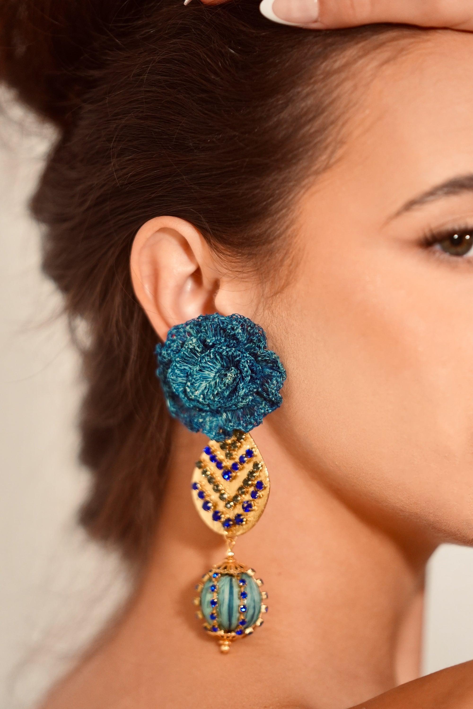Close-up of a woman wearing a blue and gold earring.