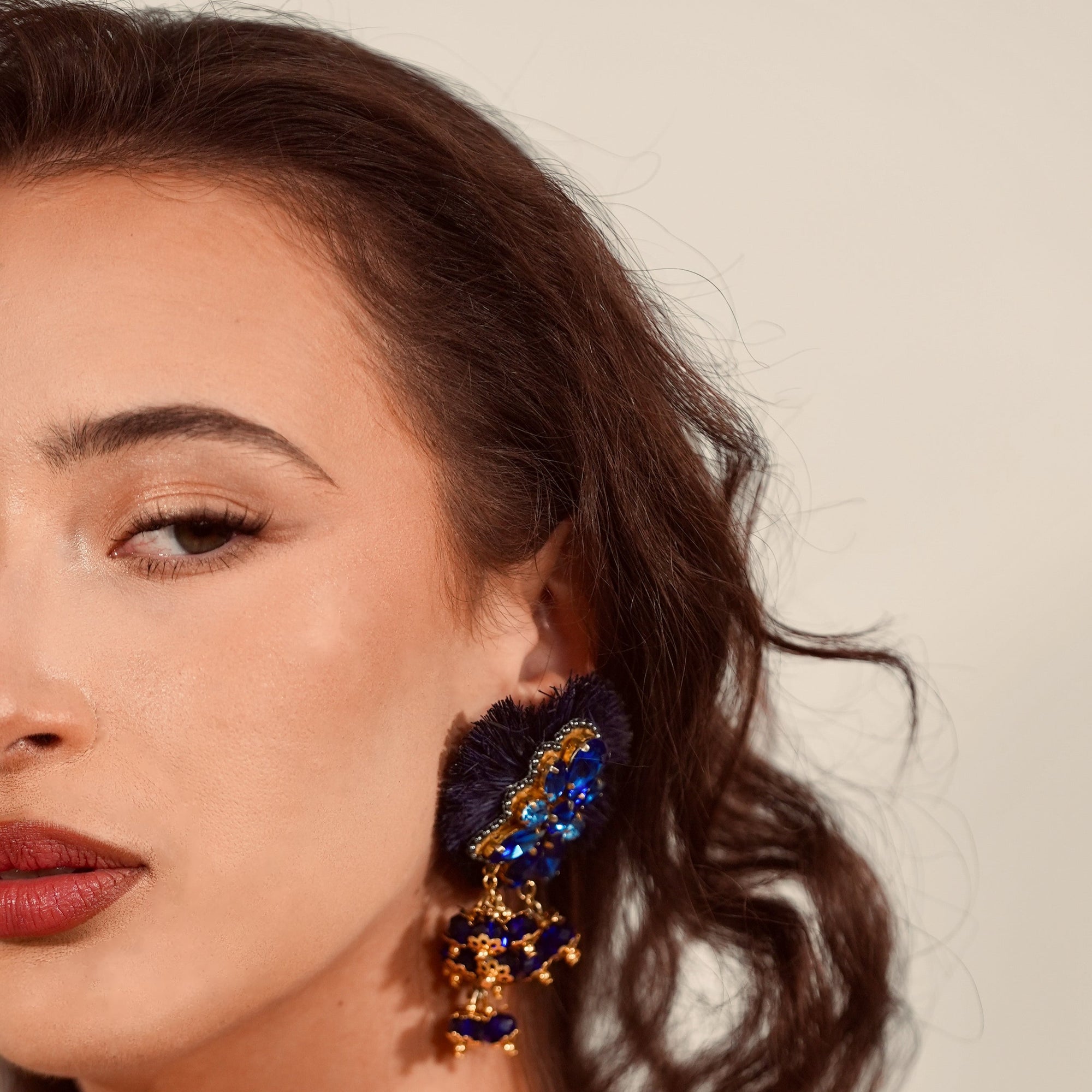 Close-up of a woman wearing a pair of earrings with blue and gold details.