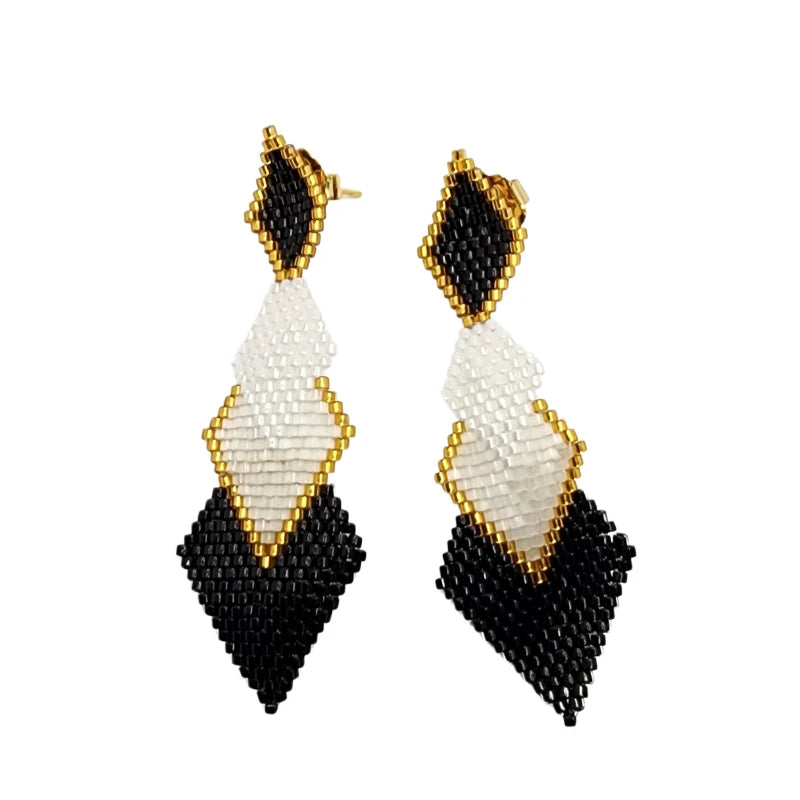 These white, black, and gold glass bead earrings feature a striking geometric rhombus-shaped structure paired with a flowing waterfall design.