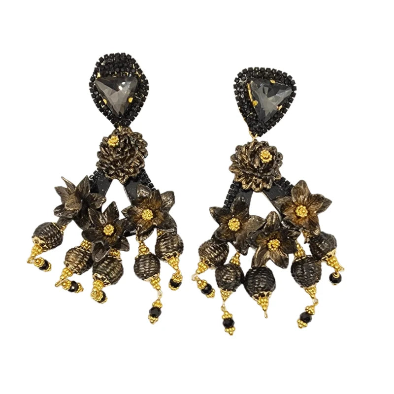 A pair of black and gold floral design earrings with intricate details and drop dangle gemstones.