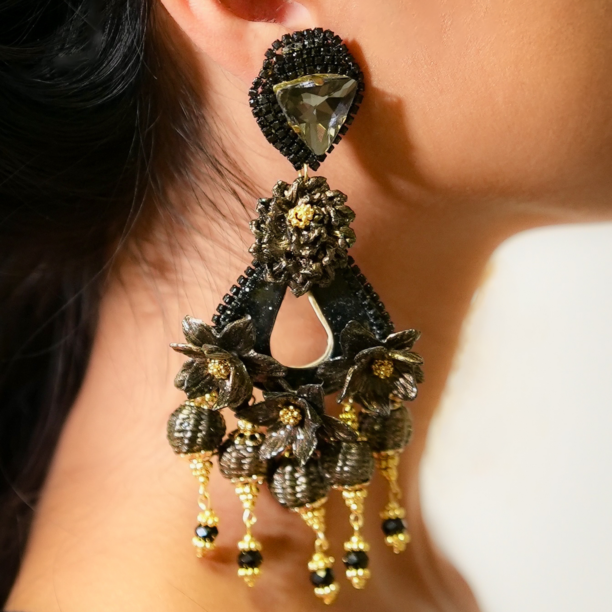 Close-up of an ornate earring with a dark gemstone and gold accents.