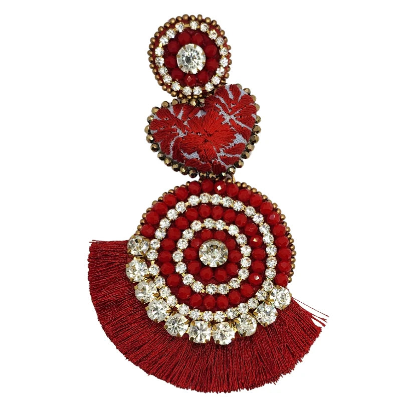 These vibrant earrings blend red beads and sparkling crystals in a charming circular design. Featuring bright gemstones, textured floral shapes