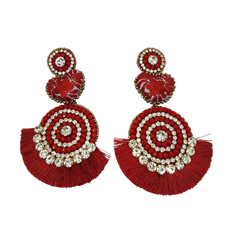 These vibrant earrings blend red beads and sparkling crystals in a charming circular design. Featuring bright gemstones, textured floral shapes