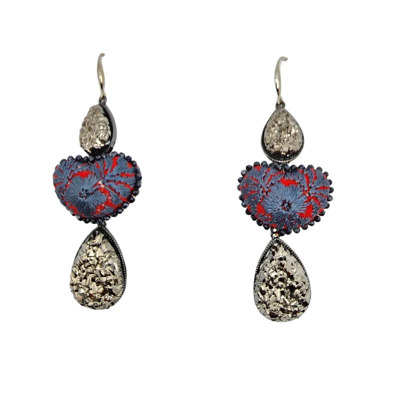 These exquisite earrings showcase a vibrant red heart with intricate embroidery in light blue, reflecting nature's delicate beauty.