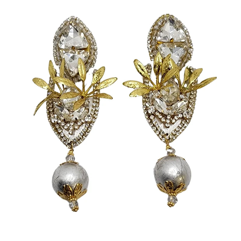 These earrings, crafted in the shape of a shield by Colombian artisans, feature totumo painted in silver. 