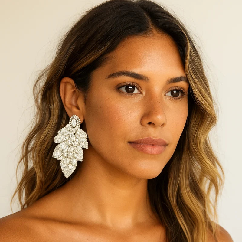Woman wearing a pair of large, ornate earrings against a neutral background